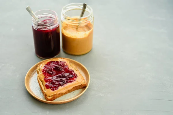 Peanut butter jelly sandwich on modern plate and grey concrete background