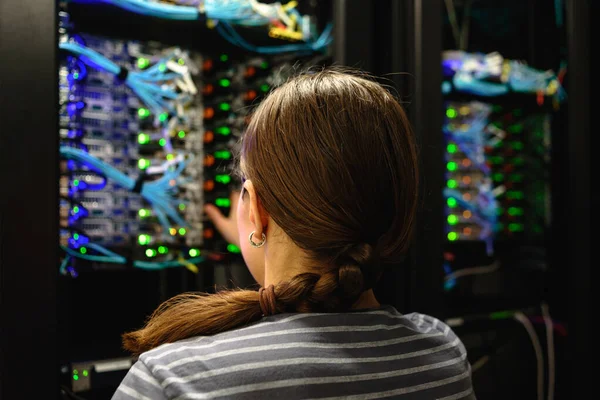 Woman network engineer near working server rack. Data center in modern IT company