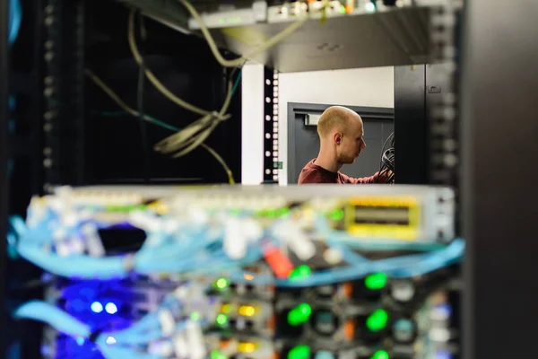 Man data center technician performing server maintenance. Replacing cables,