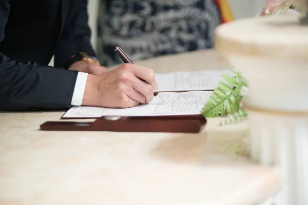 Groom assina certidão de casamento com uma caneta — Fotografia de Stock