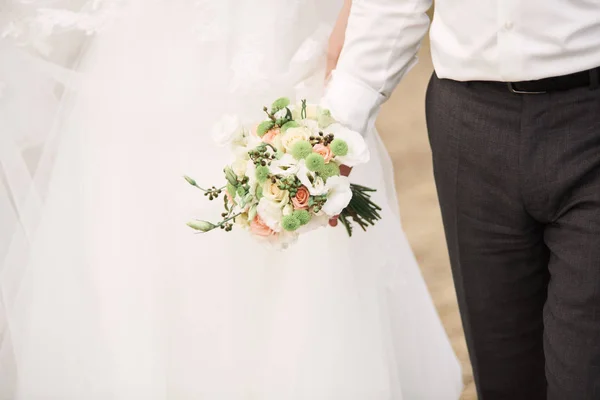 Bouquet de mariée. Mariée et marié tenant la main . — Photo