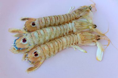 Pembe tabakta üç çiğ karides.