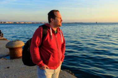 adam gün batımında deniz kıyısında duruyor