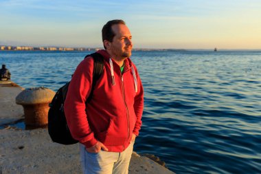 adam gün batımında deniz kıyısında duruyor