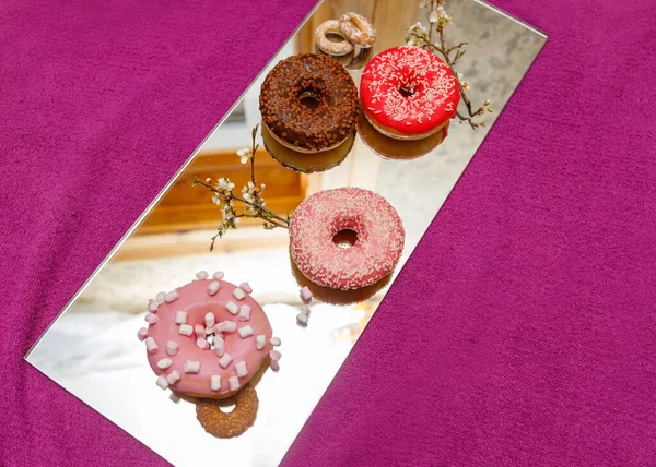 Mehrfarbige Donuts Auf Einer Spiegeloberfläche Auf Einem Rosa Stoffhintergrund Von — Stockfoto