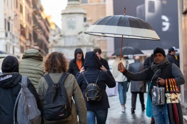 Rome, Italy - March 4, 2020: Umbrella vendor in the historic center. On a rainy day, an immigrant sells his umbrellas to citizens and tourists who stroll on the street.