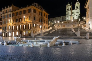 Piazza di Spagna ve Barcaccia çeşmesi, şehrin sokak lambalarıyla aydınlatılır. Koronavirüs acil durumu nedeniyle meydan alışılmadık bir şekilde terk edilmiş görünüyor..