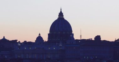 Sunset on the skyline of Rome city, with the dome of St. Peter's Cathedral in the center. Intense yellow-orange color and horizon against the light.