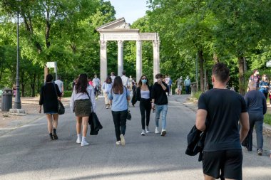 Roma, İtalya - 10 Mayıs 2020: Villa Borghese, halk parkında koruyucu maskeler takarak yürüyen insanlar. Coronavirüs salgınına yönelik kısıtlamaların hafifletilmesinden sonraki ilk pazar..