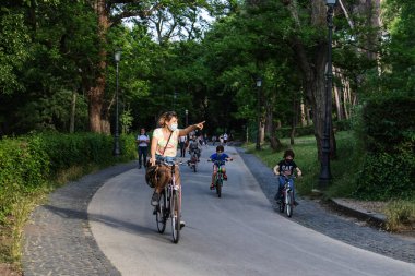 Roma, İtalya - 10 Mayıs 2020: Villa Borghese, halk parkı caddesinde insanlar bisiklete biniyor ya da geziniyor. Salgının sona ermesinden sonraki ilk pazar serbest..