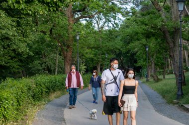 Roma, İtalya - 10 Mayıs 2020: Villa Borghese, halk parkında koruyucu maskeler takarak yürüyen insanlar. Coronavirüs salgınına yönelik kısıtlamaların hafifletilmesinden sonraki ilk pazar..