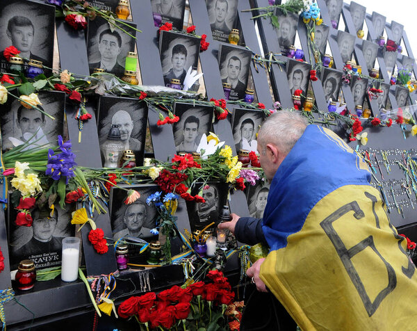 A man with the Ukrainian flag lays flowers at the memorial to activists of Euromaidan or Heroes of Heavenly Hundreds who were killed in Kiev, February 20, 2020. 