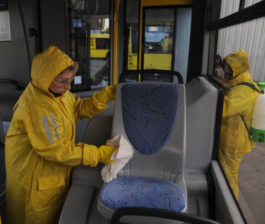 Koruyucu giysili bir işçi, 13 Mart 2020 'de Kiev' deki otobüs durağında Coronavirus Covid-19 'a karşı önleyici tedbir olarak yolcu otobüsünü dezenfekte eder..