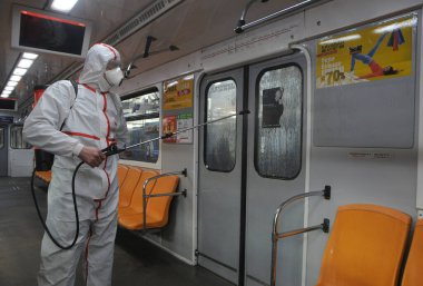 Koruyucu ekipman işçisi 16 Mart 2020 'de Kiev' deki otobüs durağında Coronavirus Covid-19 'a karşı önleyici önlem olarak Kiev Metro arabalarının dezenfekte edilmesi için dezenfektan sıkar..