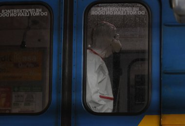 Koruyucu ekipman işçisi 16 Mart 2020 'de Kiev' deki otobüs durağında Coronavirus Covid-19 'a karşı önleyici önlem olarak Kiev Metro arabalarının dezenfekte edilmesi için dezenfektan sıkar..