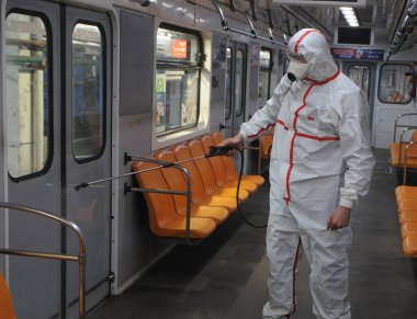 Koruyucu ekipman işçisi 16 Mart 2020 'de Kiev' deki otobüs durağında Coronavirus Covid-19 'a karşı önleyici önlem olarak Kiev Metro arabalarının dezenfekte edilmesi için dezenfektan sıkar..