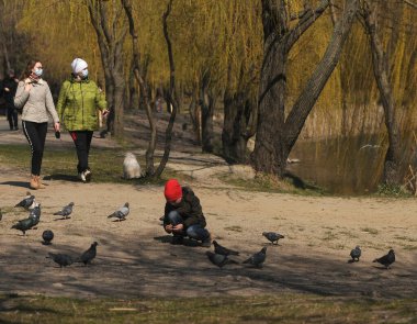 4 Nisan 2020 'de Kiev' de bir parkta bir çocuk güvercinlerin yanında oynuyor..