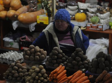 Bir kadın, 22 Ocak 2019 'da Kiev' deki Vladimir Pazarı 'nın örtülü kısmında sebze ticareti yapıyor.