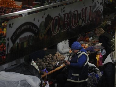 Bir kadın, 22 Ocak 2019 'da Kiev' deki Vladimir Pazarı 'nın örtülü kısmında sebze ticareti yapıyor.