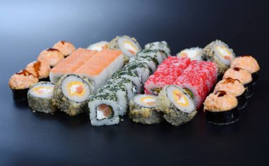 Japon pirinç balık, sebze ve zencefil ile karanlık bir arka plan üzerinde rulo