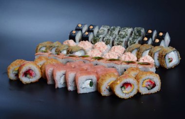 Japon pirinç balık, sebze ve zencefil ile karanlık bir arka plan üzerinde rulo