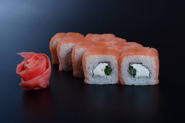 Japon pirinç balık, sebze ve zencefil ile karanlık bir arka plan üzerinde rulo