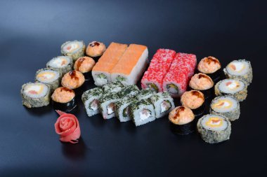 Japon pirinç balık, sebze ve zencefil ile karanlık bir arka plan üzerinde rulo