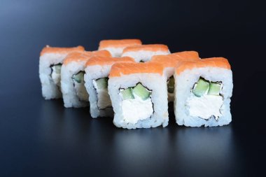 Japon pirinç balık, sebze ve zencefil ile karanlık bir arka plan üzerinde rulo