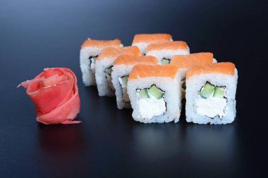 Japon pirinç balık, sebze ve zencefil ile karanlık bir arka plan üzerinde rulo