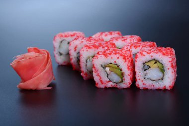 Japon pirinç balık, sebze ve zencefil ile karanlık bir arka plan üzerinde rulo