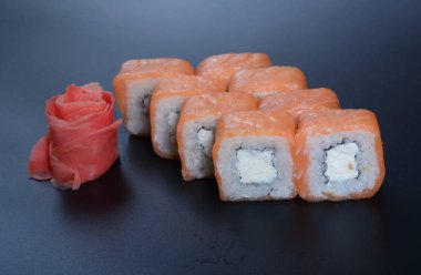 Japon pirinç balık, sebze ve zencefil ile karanlık bir arka plan üzerinde rulo