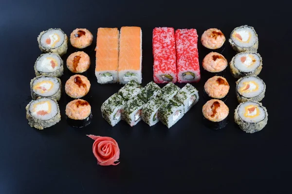 Japon pirinç balık, sebze ve zencefil ile karanlık bir arka plan üzerinde rulo