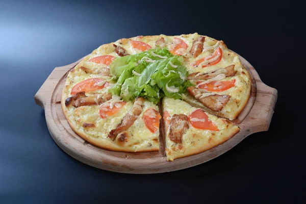Pizza with tomatoes, cheese, meat and fish on dark background