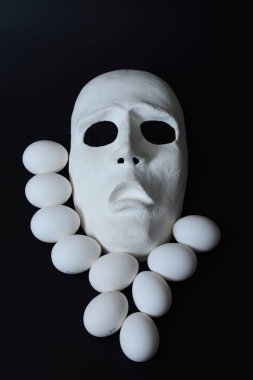 Tavuk yumurta yumurta kapsayıcıyla beyaz tiyatro maskesi yatıyor