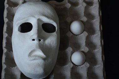 Tavuk yumurta yumurta kapsayıcıyla beyaz tiyatro maskesi yatıyor