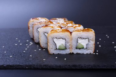 Japon pilavı ve deniz ürünleri kreması koyu bir zemin üzerinde uzanıyor.
