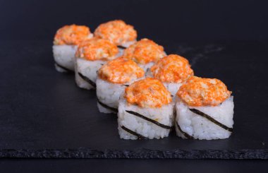 Japon pilavı ve deniz ürünleri kreması koyu bir zemin üzerinde uzanıyor.