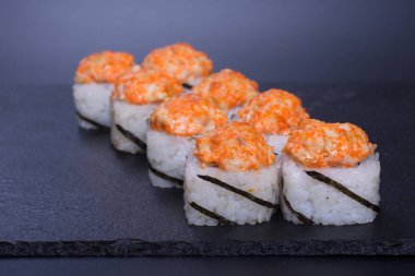 Japon pilavı ve deniz ürünleri kreması koyu bir zemin üzerinde uzanıyor.