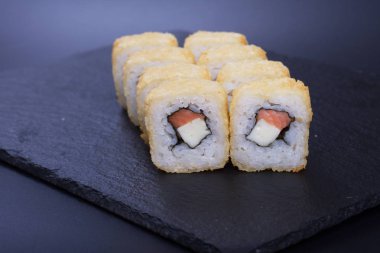 Japon pilavı ve deniz ürünleri kreması koyu bir zemin üzerinde uzanıyor.