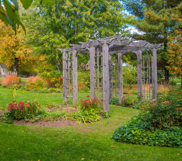 Fából készült arch virágos kertben. Arborétum, többek között a zöld kert esküvői . — Stock Fotó