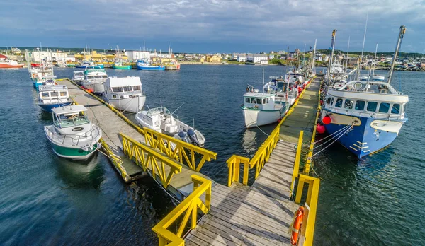 Bona Vista, Newfoundland fishing village.  Wide angle view of L shaped dock. Boats tied up - in for the day, bright sunshine on calm coastal water. — Stock Photo, Image