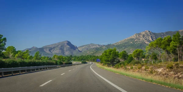 Voiture solitaire descend l'autoroute à travers les contreforts côtiers et les montagnes d'Espagne . — Photo