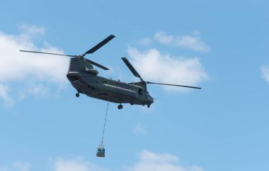 Double rotor, heavy airlift, military helicopter, in flight, carrying cargo. clipart