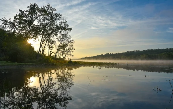 Brillante alba sulla nebbiosa, nebbiosa mattina d'estate sul lago di Corry . — Foto Stock