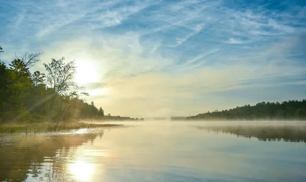 Brillante alba sulla nebbiosa, nebbiosa mattina d'estate sul lago di Corry . — Foto Stock