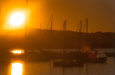 Akşamları Ibiza Marina limanındaki yelkenliler ve küçük yatlar. Günün sonunda muhteşem altın sıcak günbatımı. 