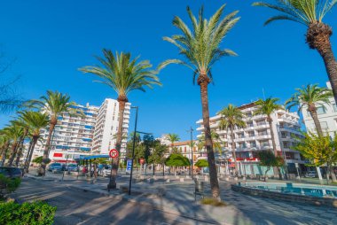 Parlak sabah güneş ışığında şehir kare yaya park ve Çeşme. Arka plan için otel bulundu. İnsanlar bir stand Meydanı'nda bir taksi bekler.