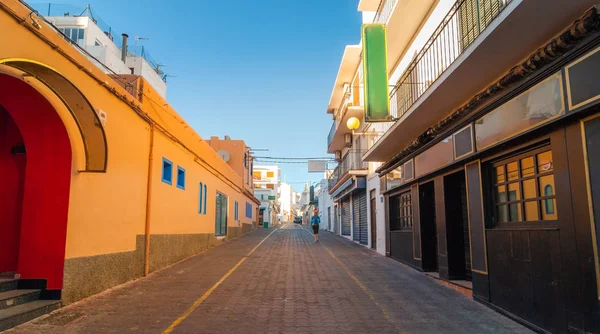 Tons quentes brilhantes do sol indireto da tarde. Homem caminha pela estrada nas ruas de Santo Antônio de Portmany, Ibiza, Ilhas Baleares, Espanha . — Fotografia de Stock