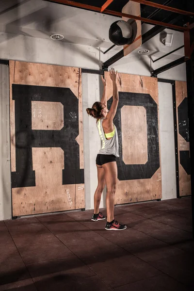 Femme faisant de l'exercice en lançant une balle dans une salle de gym . — Photo