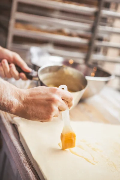 Smearing raw dough  with brush in yolk — Stock Photo, Image